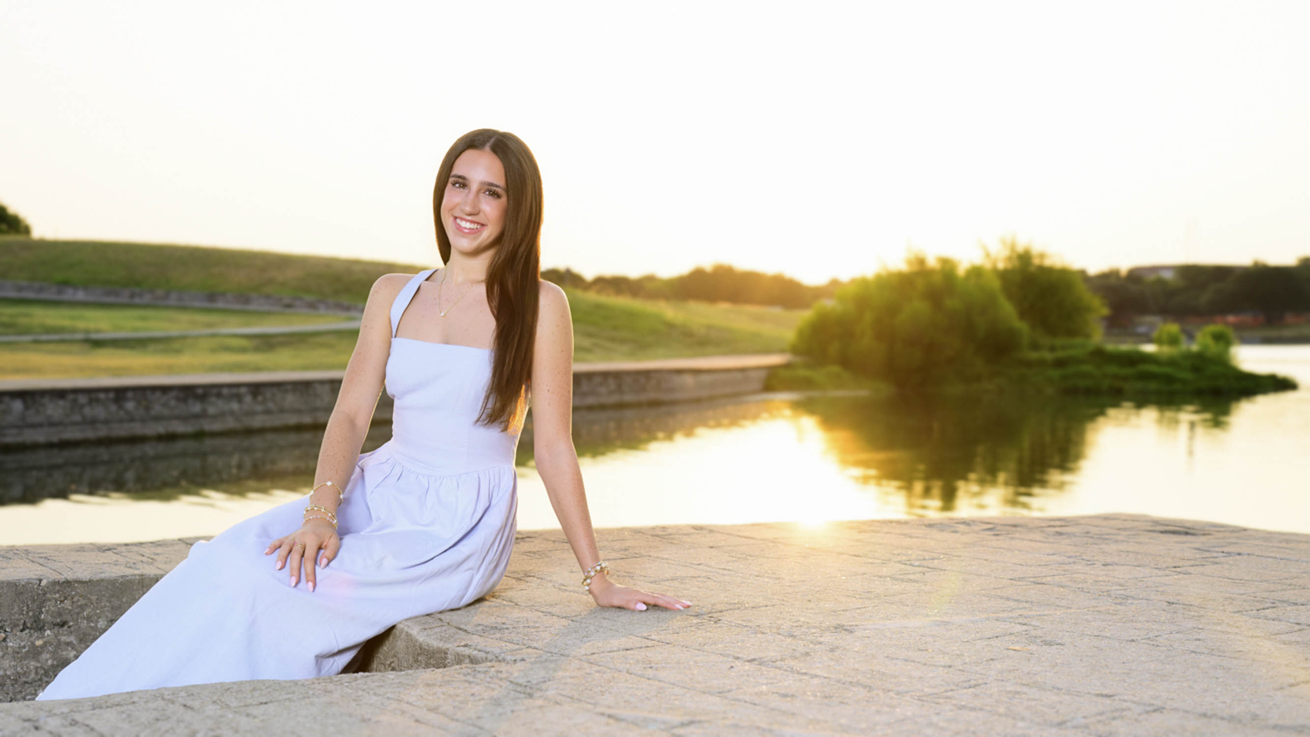 ImageStella celebrating her senior year with an outdoor portrait at Adriatica in McKinney, Texas. A joyful photo session at sunrise.